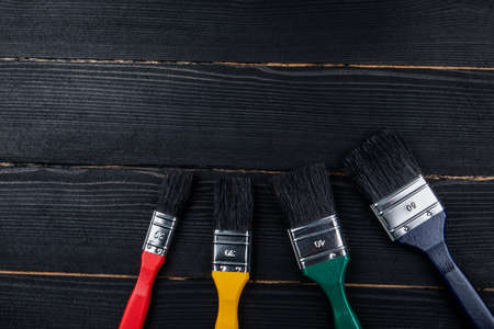 Paint brushes of different sizes and colors on a dark wooden backgroundの写真素材