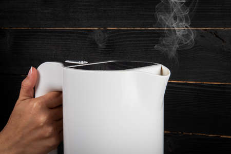 Hot water kettle in a womans handの写真素材