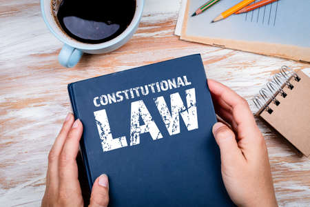 Constitutional Law. Book in woman hand. Office desk