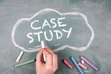 Case study concept. Pieces of colored crayons and a human hand on a green chalk boardの写真素材