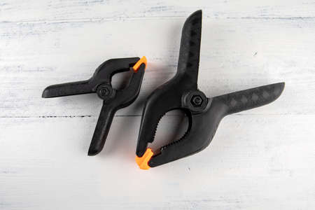 Black plastic clamps on a white wooden backgroundの写真素材