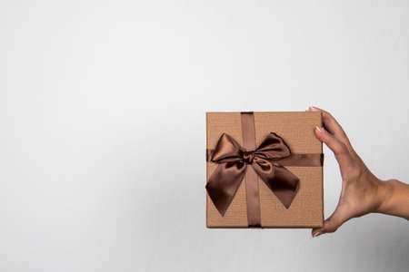 Brown gift box in a womans hand on a light backgroundの写真素材