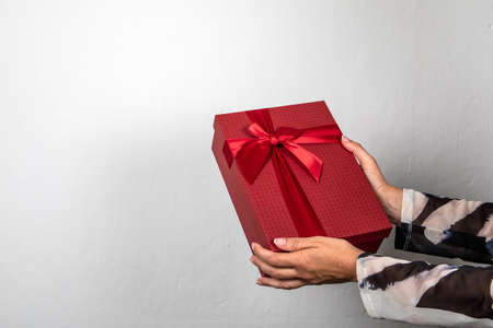 Red gift box in womans hands. Christmas, birthday or Valentines Day conceptの写真素材