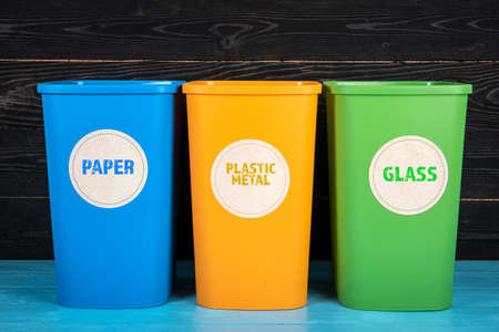 Paper, Plastic Metal and Glass waste sorting containers on a wooden backgroundの写真素材