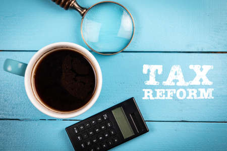 Tax Reform. Coffee mug, magnifying glass and calculator on a wooden backgroundの写真素材