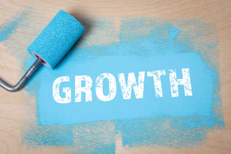 GROWTH. Blue color and paint roller on a wooden backgroundの写真素材