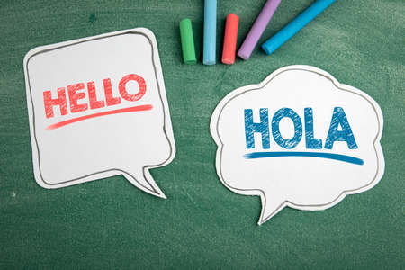 In English and Spanish the word Hello. Speech bubbles on a chalk boardの写真素材