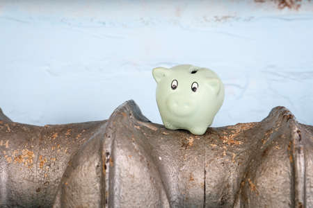 Piggy bank on cast iron radiators, heater. Household heating expensesの写真素材