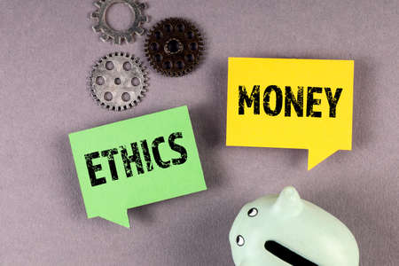 Money and Ethics concept. Speech bubbles, savings bank and gears on a gray backgroundの写真素材
