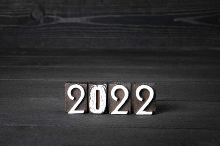2022 New Year. Wooden blocks on a dark textured wooden background