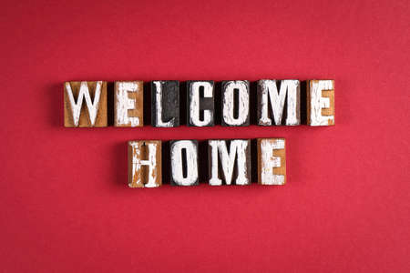 Welcome Home. Words from wooden letters on a red paper backgroundの写真素材