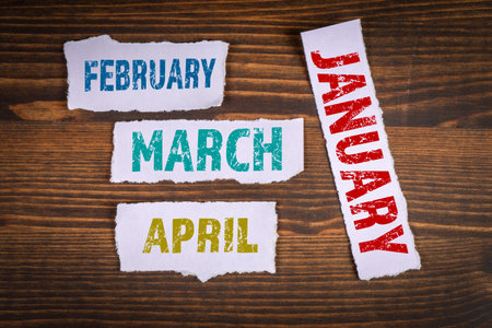 January February March and April. Torn paper on a wooden backgroundの写真素材
