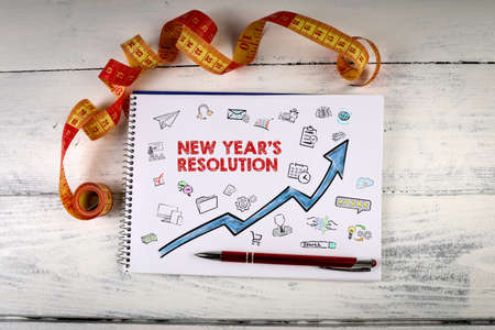 New Years resolution. Notebook and measuring tape on a wooden background