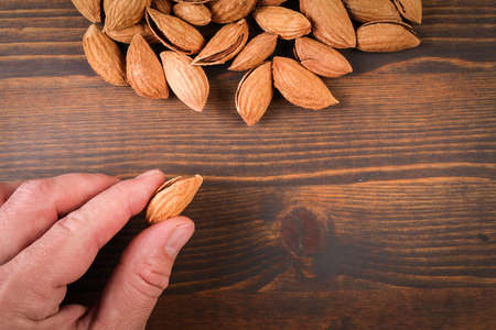 Almonds in a man s hand. Dark wood texture backgroundの写真素材
