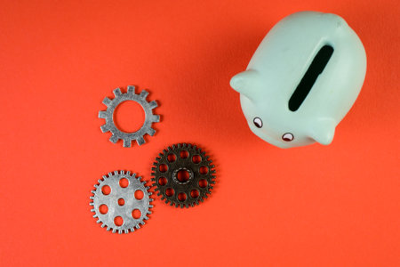 Gears and piggy bank on a red background. Money saving concept
