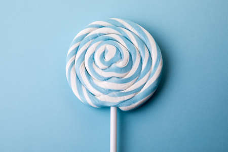 Blue lollipop on blue background. Party and unhealthy foodの写真素材