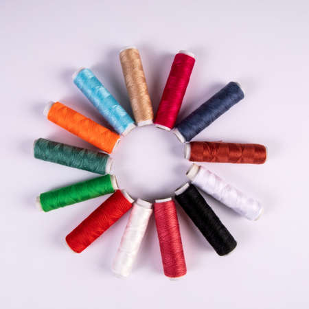 Spools of thread for sewing in different colors on white background. Round, sun like shapeの写真素材