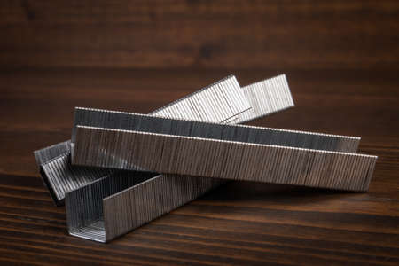 Metal staples for staple guns on a wooden texture backgroundの写真素材