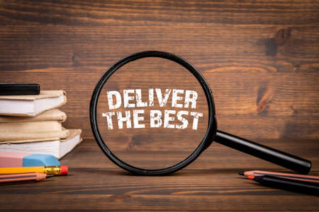 Deliver the best. Magnifying glass and books on a wooden backgroundの写真素材