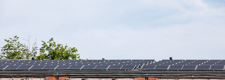 Many solar panels on the roof of a store or production building. Sunny day