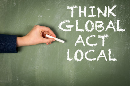 Think global act local. Text on a green chalkboard backgroundの写真素材