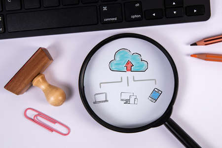 Cloud technology concept. Magnifying glass and computer keyboard on office tableの写真素材