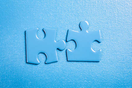 Blue puzzle pieces on a blue textured backgroundの写真素材