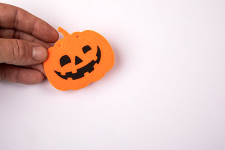 Halloween holiday decor. Orange pumpkin with the face of a man in his hands on a white backgroundの写真素材