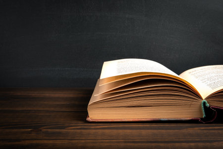 An open educational or literary book on a wooden table