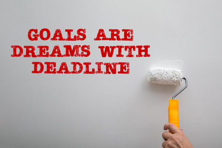 Goals Are Dreams With Deadline. Paint a white wall with a paint rollerの写真素材