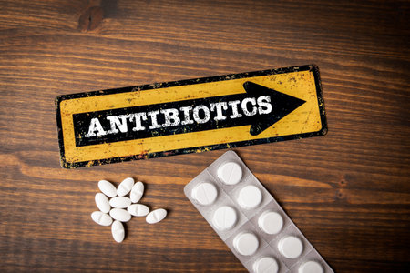 Antibiotics Concept. Yellow direction sign with arrow and text. Pills on a wooden backgroundの写真素材