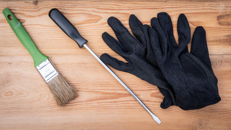 Brush, screwdriver and black gloves on wooden texture backgroundの写真素材