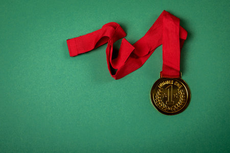 Gold medal with a red ribbon on a green background. Copy space