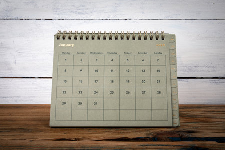 JANUARY 2024 cardboard desk calendar and planner on a wooden texture table