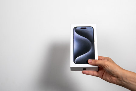 Iphone 15 Pro in a box in the hand on a white background. Demonstrating new smartphoneのeditorial素材