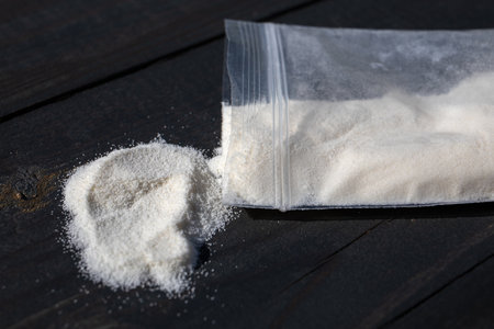 A bag of white powder on a wooden texture table. Image for prohibited substances, addiction conceptの写真素材