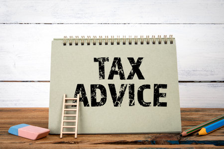 Tax Advice. Green notepad on wooden texture table and white backgroundの写真素材