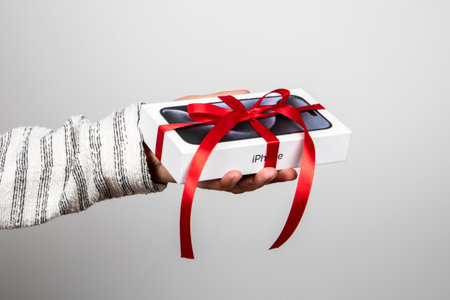Box of the Iphone 15 Pro. Gift with a red ribbon in the hand