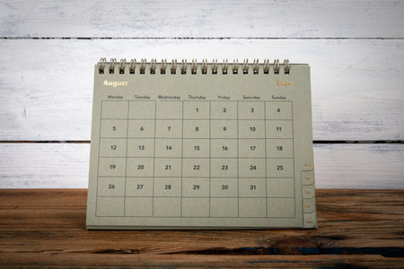 AUGUST 2024 cardboard desk calendar and planner on a wooden texture tableの写真素材