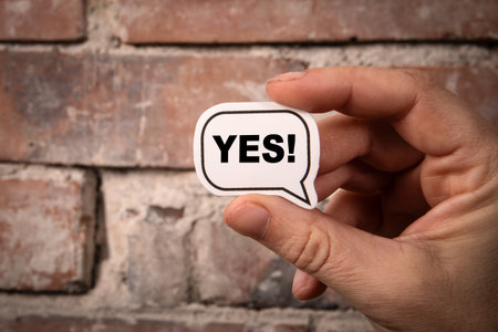 Yes Concept. Speech bubble with text in hand on brick backgroundの写真素材