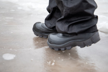 Walk with boots on the ice, close-up. Slippery roads in winter