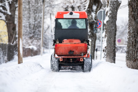 Snow plow shoveling snow on the sidewalk, harsh winter, view from backの写真素材