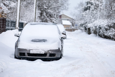 Snow-covered car in the street covered with a thick layer of snow on a winter dayの写真素材