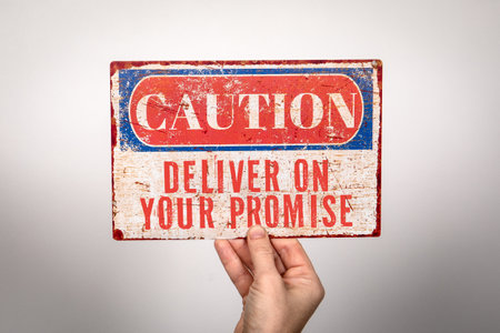 Deliver On Your Promise. Metal warning sign in a womans hand on a white backgroundの写真素材