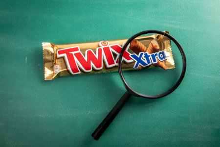 Twix XTRA bars and magnifying glass on a green chalkboard background. Twix bars are produced by Mars Incorporatedのeditorial素材