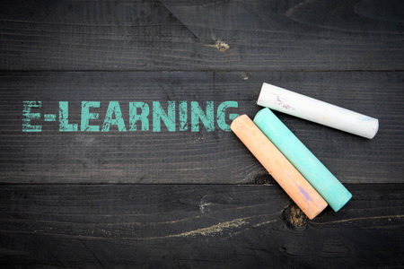 E-Learning Concept. Text and pieces of chalk on a dark wood texture backgroun