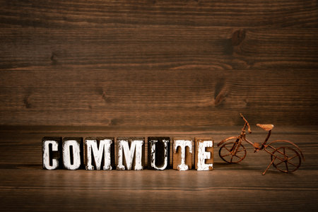 COMMUTE. Text from alphabet blocks and rusty miniature bicycle on wood texture background