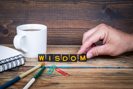 WISDOM. Old letter tiles on a wooden texture office table