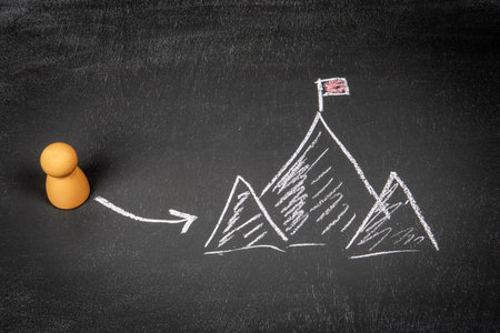 Setting and achieving goals concept. Wooden human figures on a chalkboard backgroundの写真素材