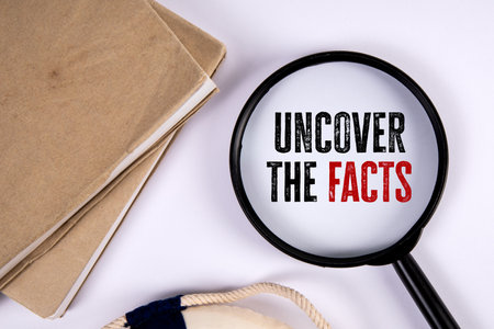 Uncover the facts. Magnifying glass and stack of books on white tableの写真素材